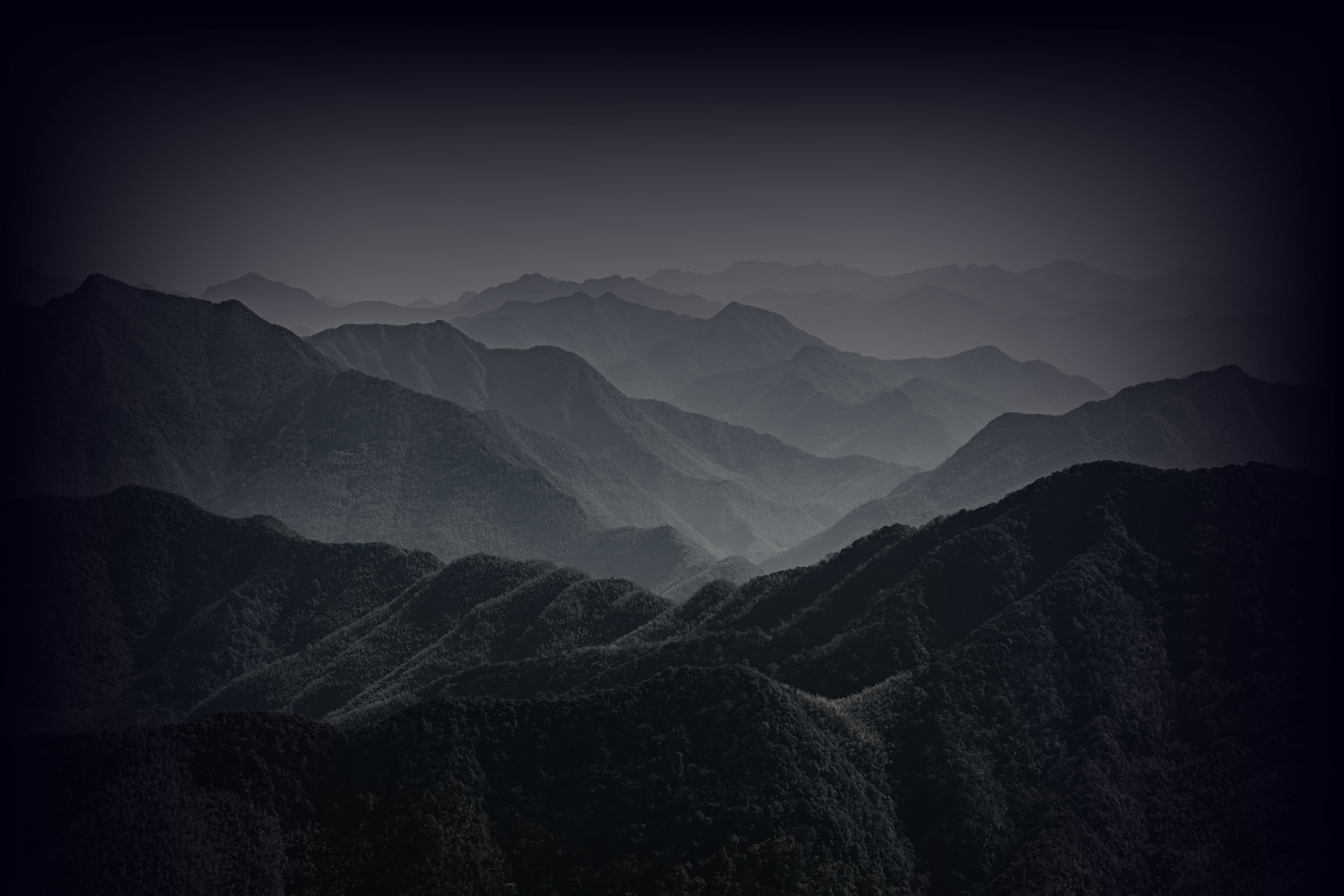 Layered mountain ridges fading into mist at dusk